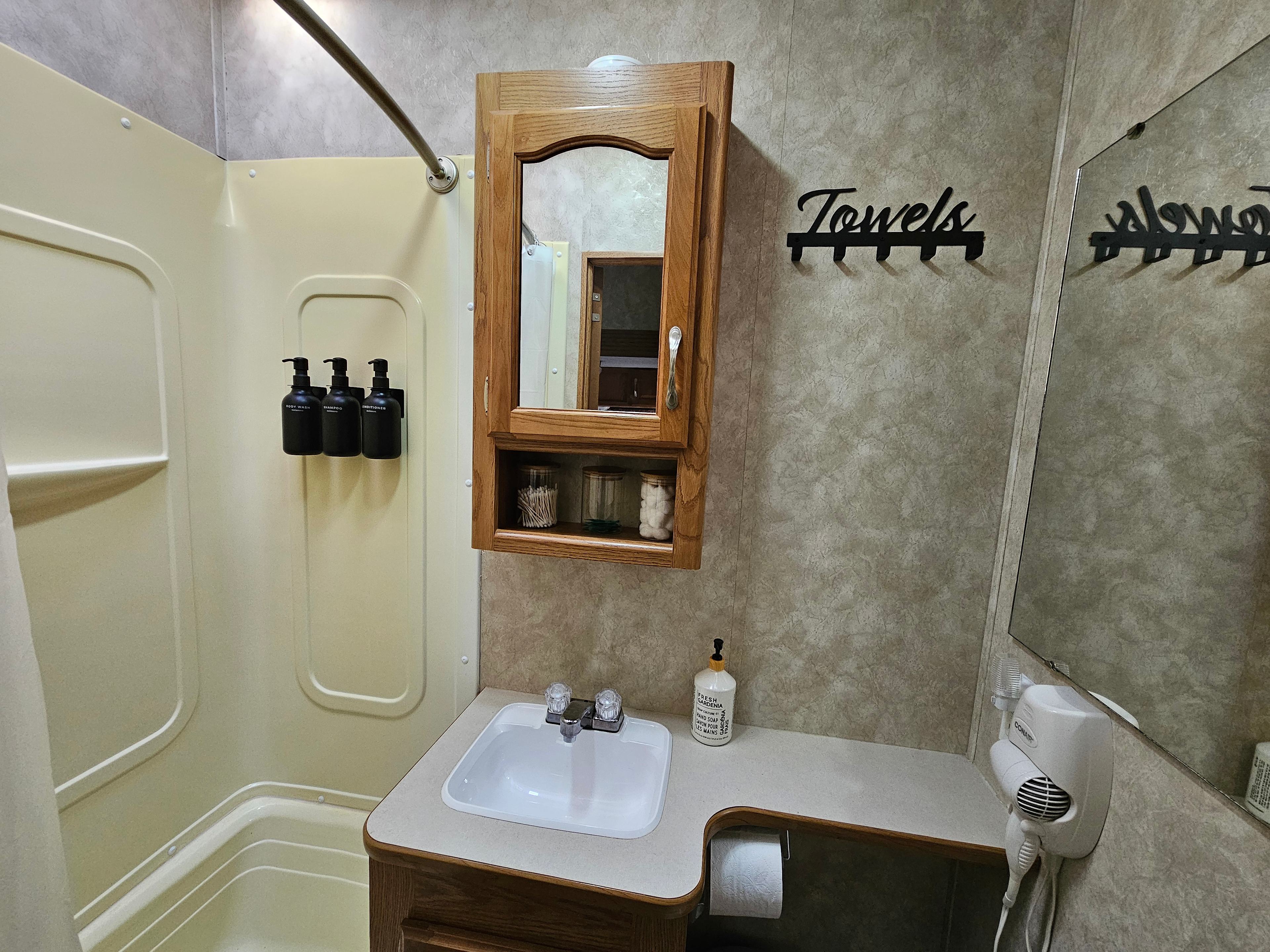 Bathroom has body wash, shampoo and conditioner to use during your stay.  
Toilet paper, hand soap cotton swabs and hairdryer are there for your convenience.  The shower and tub are RV sized but adequate for most people and they are fully hooked up with hot and cold water.