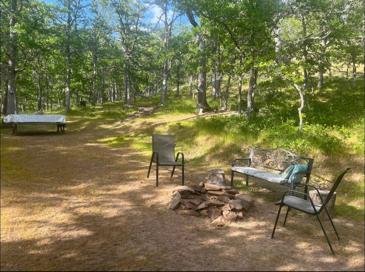 The common area contains a bench and chairs, "book nook" fire pit, compost bin, hammock and picnic table. It fits large tents, T@bs, and car campers