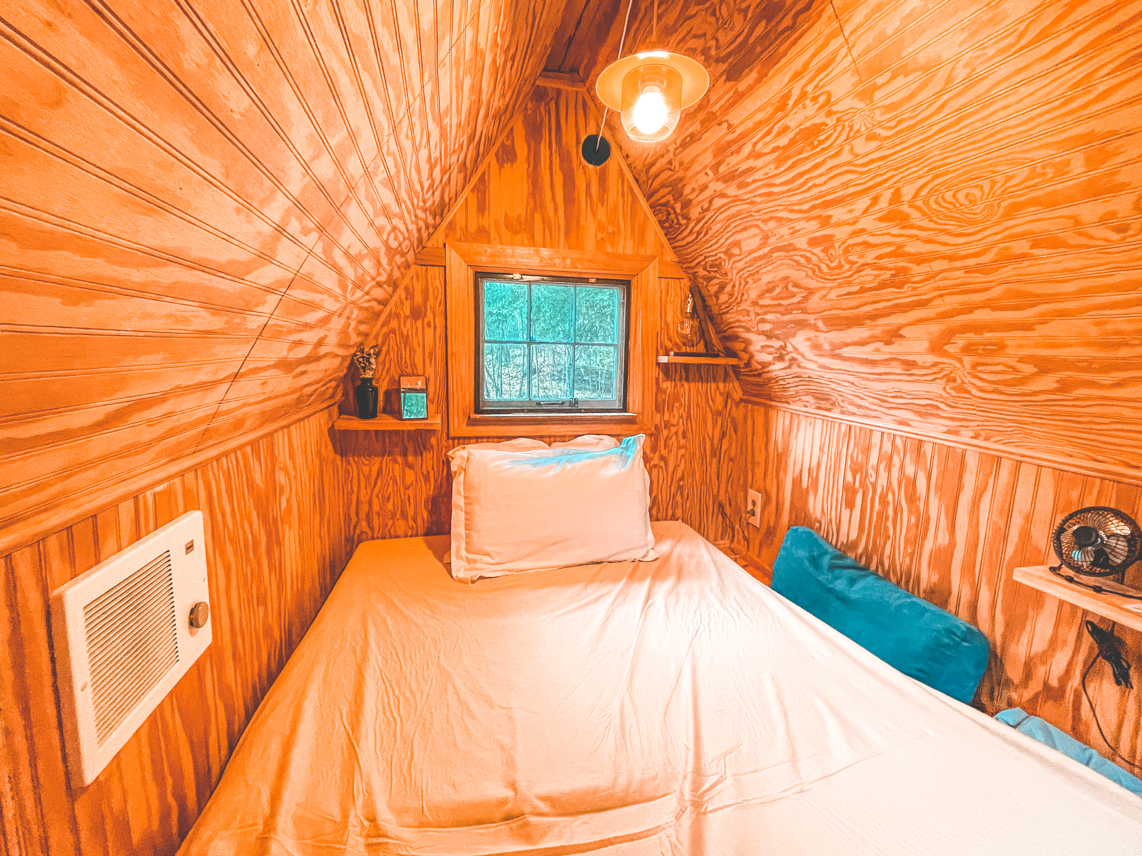 upstairs of the cabin with a full bed that sleeps 1-2 people. light, outlets, lamp, speaker, and built in heater. there's a front and back window that both open up and have screens.