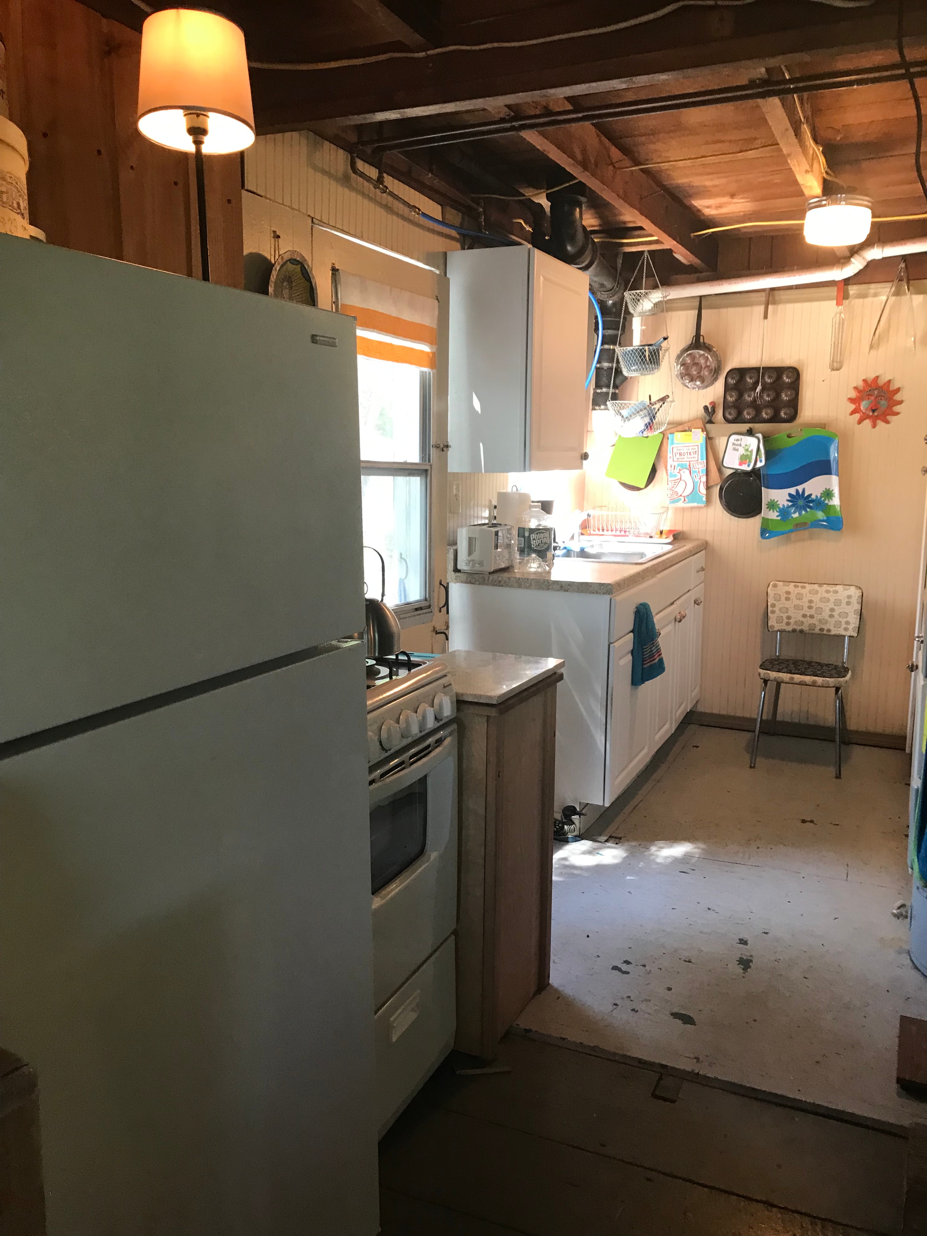 Fully equipped galley kitchen: the appliances include a propane gas range, full-size fridge with freezer compartment, large microwave and large toaster oven, coffee maker and tea kettle. The kitchen door goes out to a small deck with clothesline.
