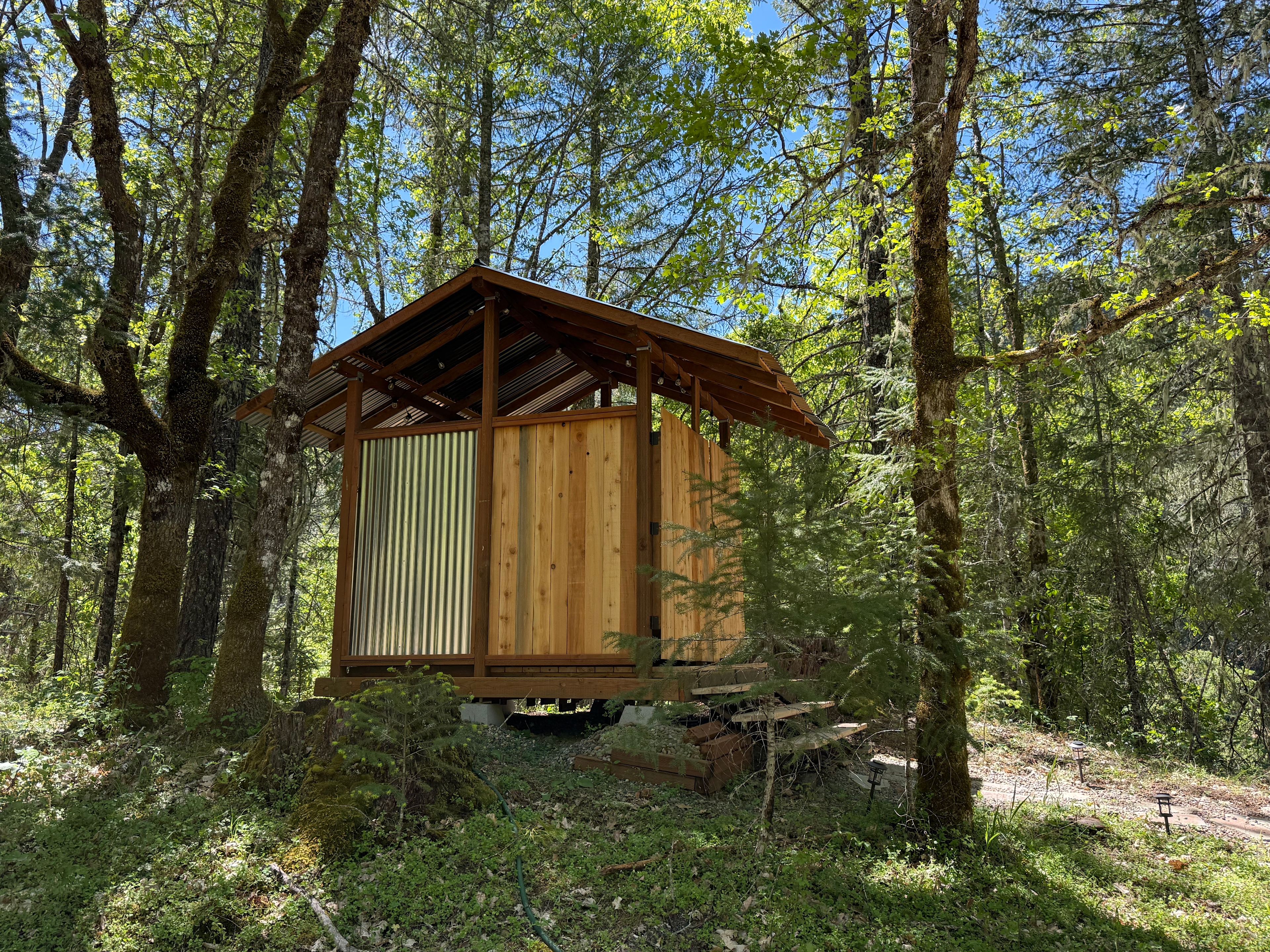 Side view of the shower house with two new showers tucked into the forest. 