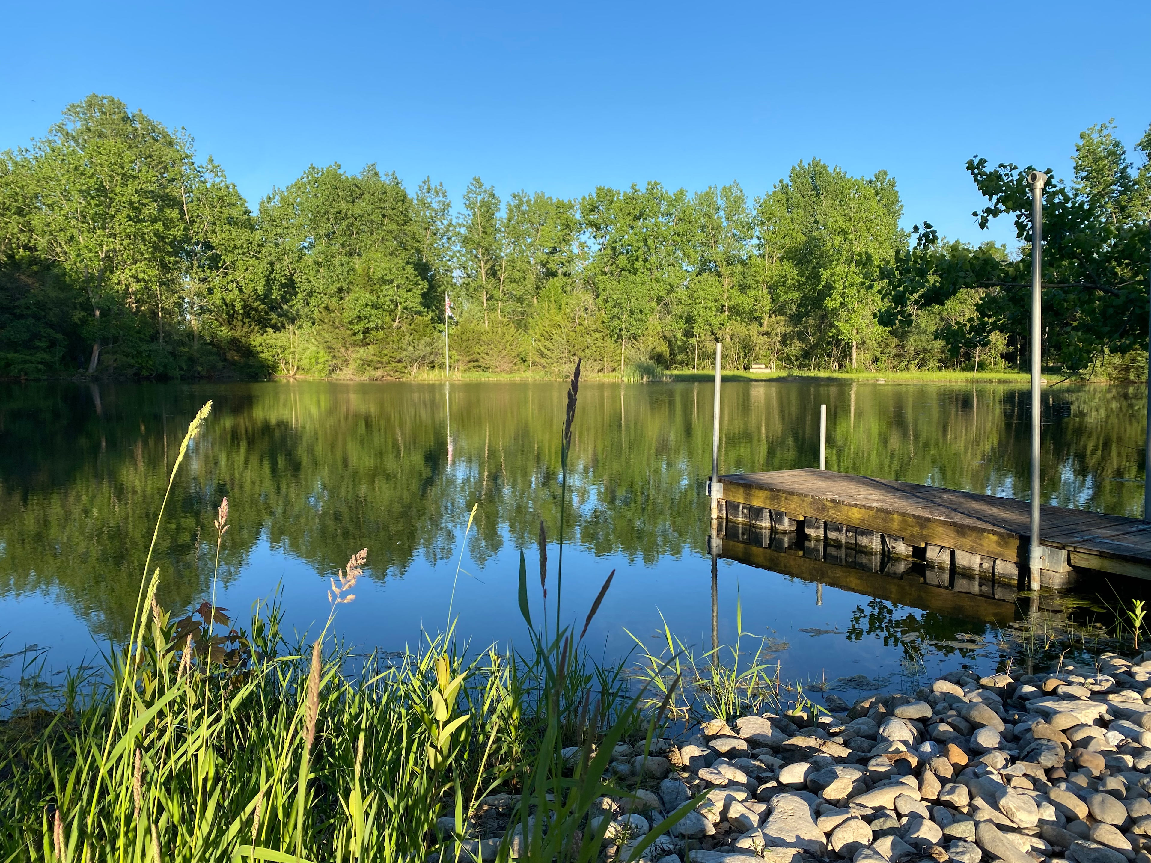 Waterfront campsite location situated at the bottom of the hill. Adjacent to former stone quarry rocky edge with ease of access to fish from the dock (catch and release), relax by the fire pit, enjoy the outdoor dining area and more. 