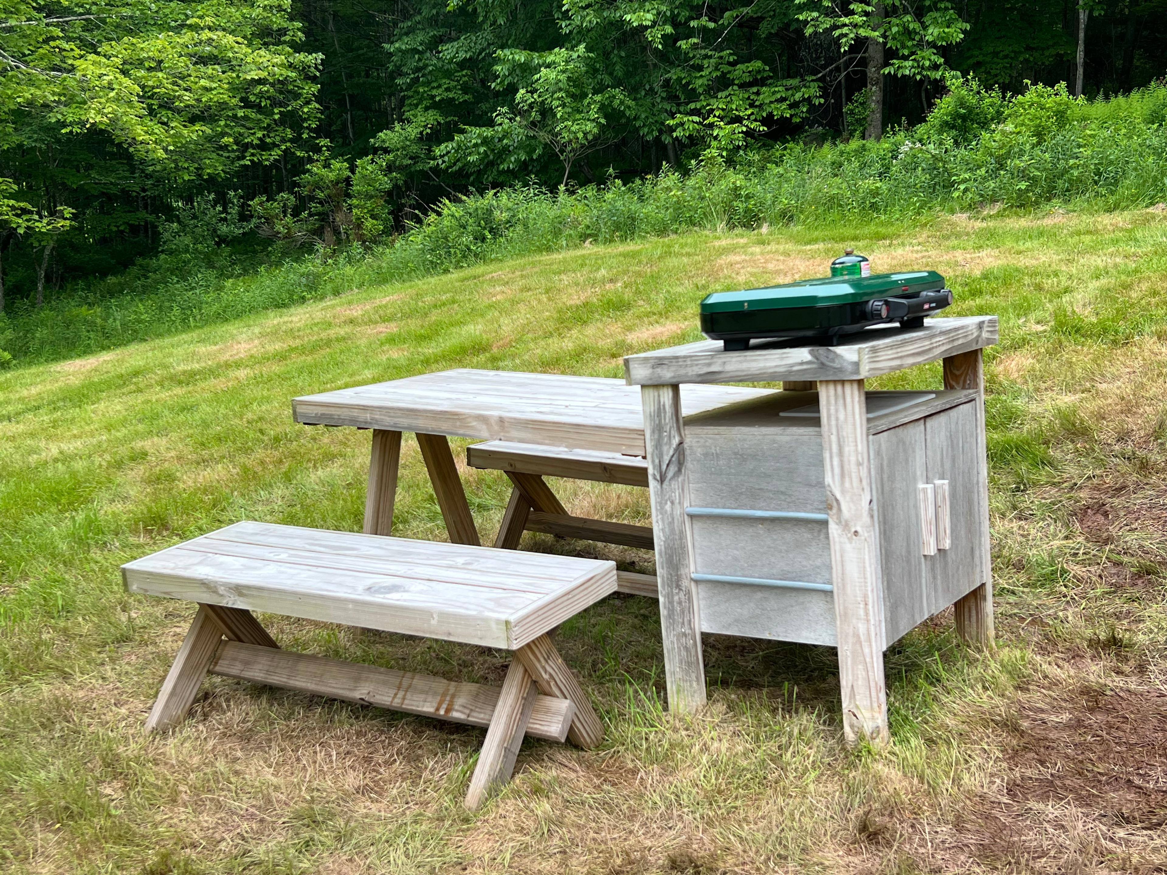 Picnic table with benches, two burner camp stove & utensil storage locker.