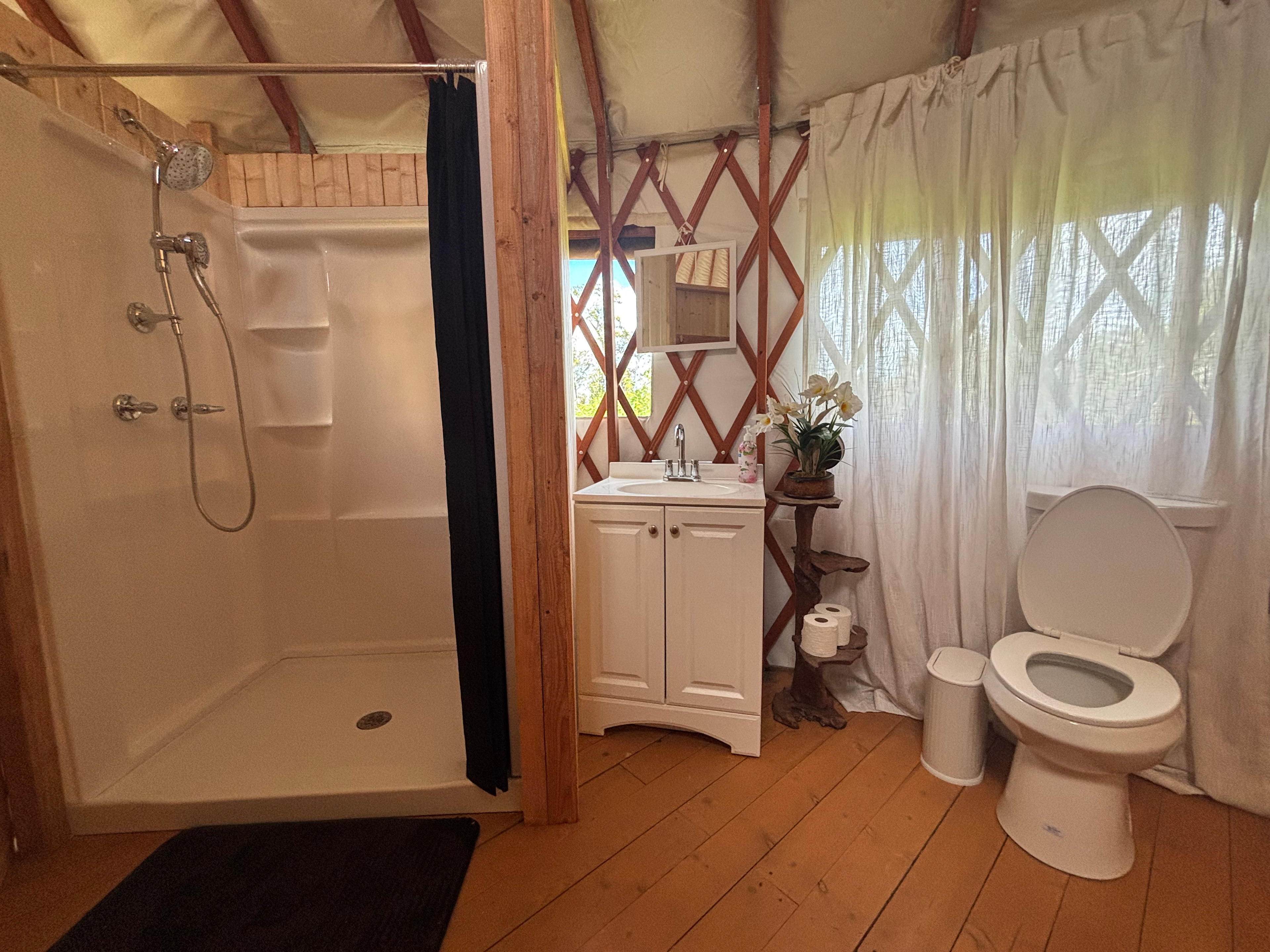 Newly renovated yurt bathroom—shower, vanity, and flushing toilet.