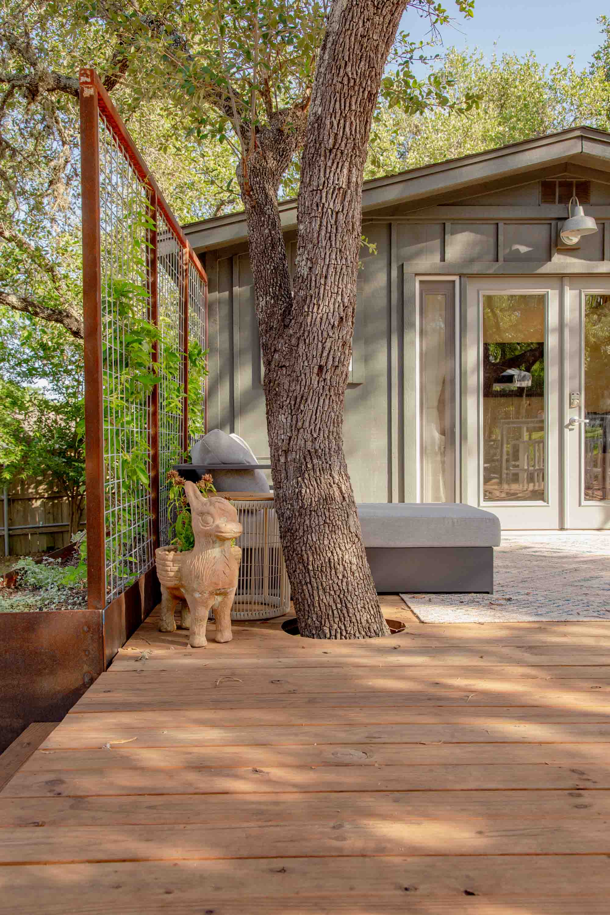 Charming details like the planted donkey statue and a tree growing through the deck add character and whimsy to this peaceful retreat.