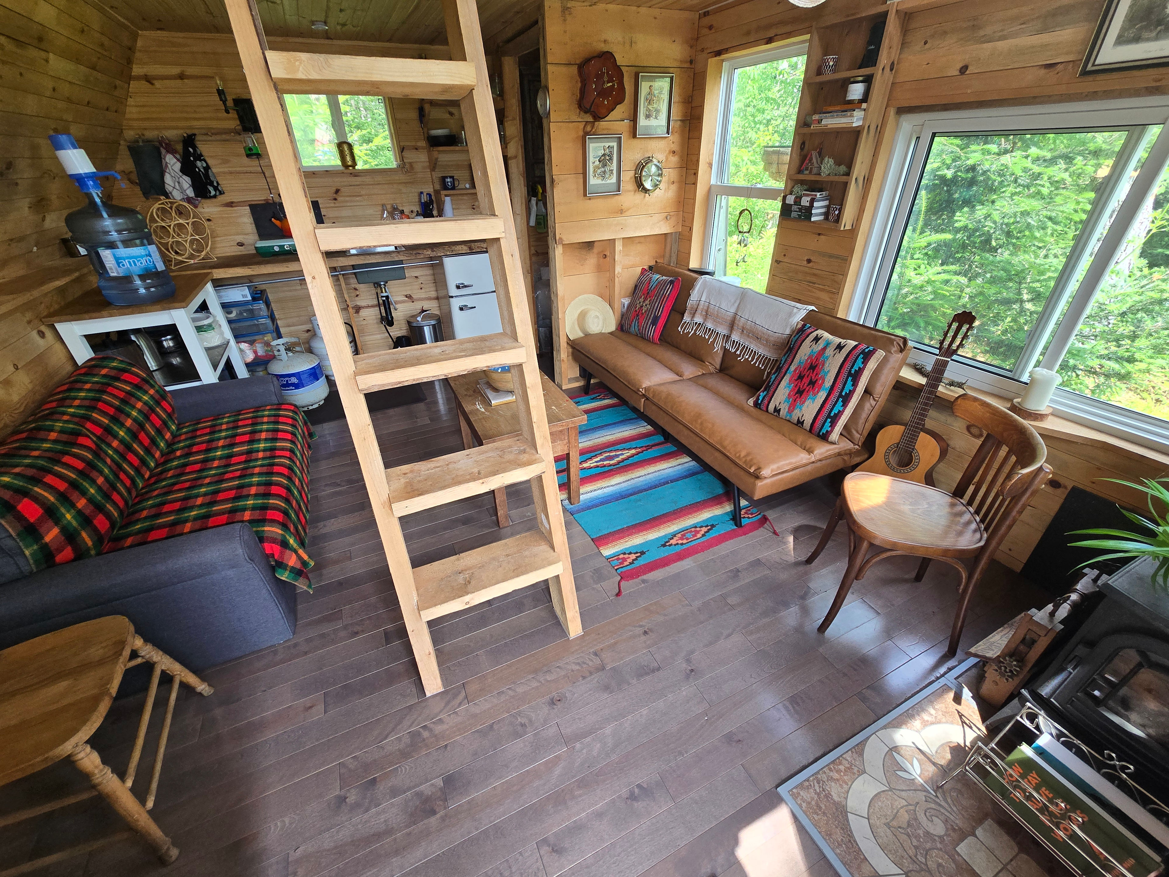 living room and kitchen at the back with gas powered coleman stove, kettle, drinking water with hand pump.