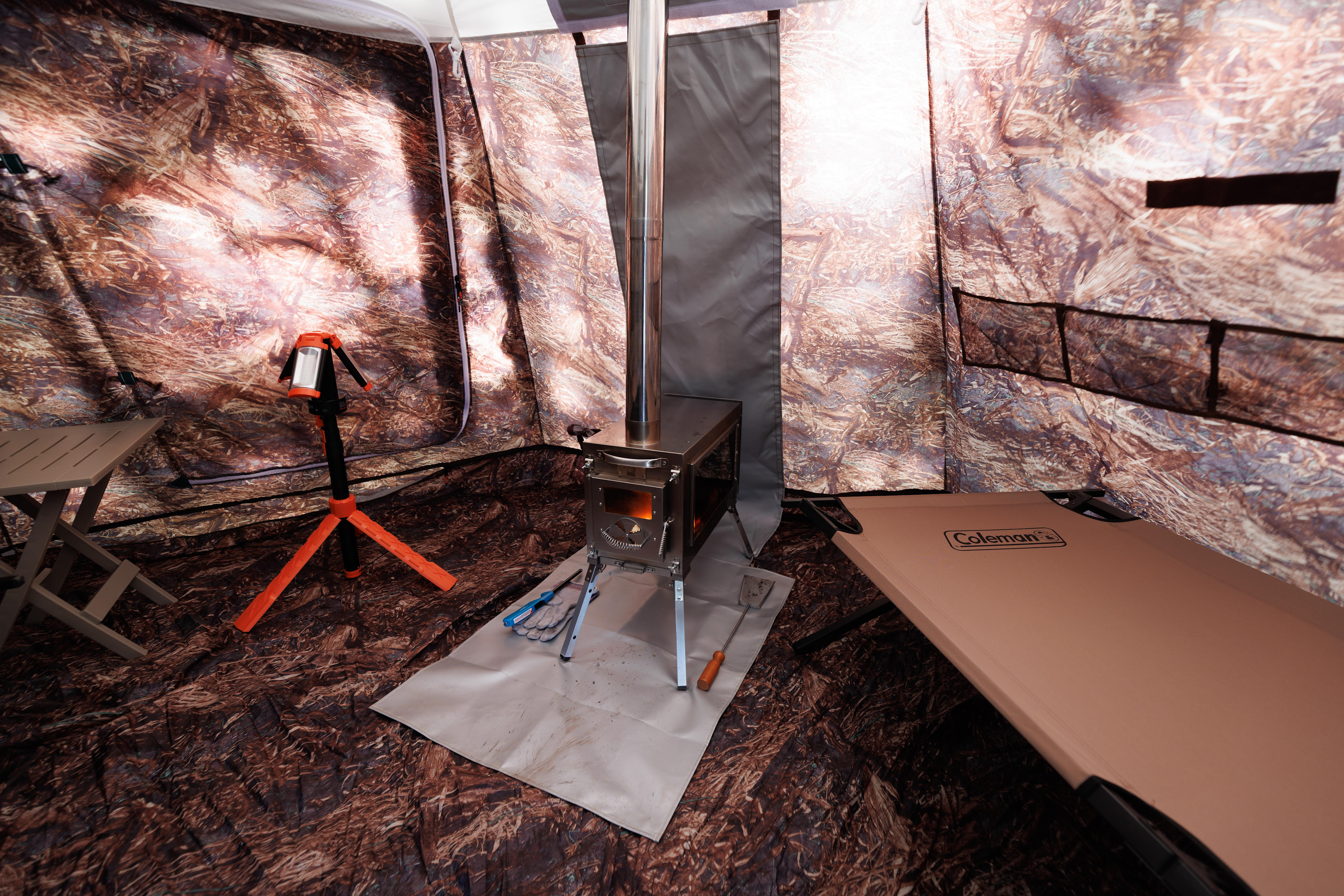 Inside the tent comes with 2 cots, a wood stove, an LED light, a small table, and 2 folding camp chairs.