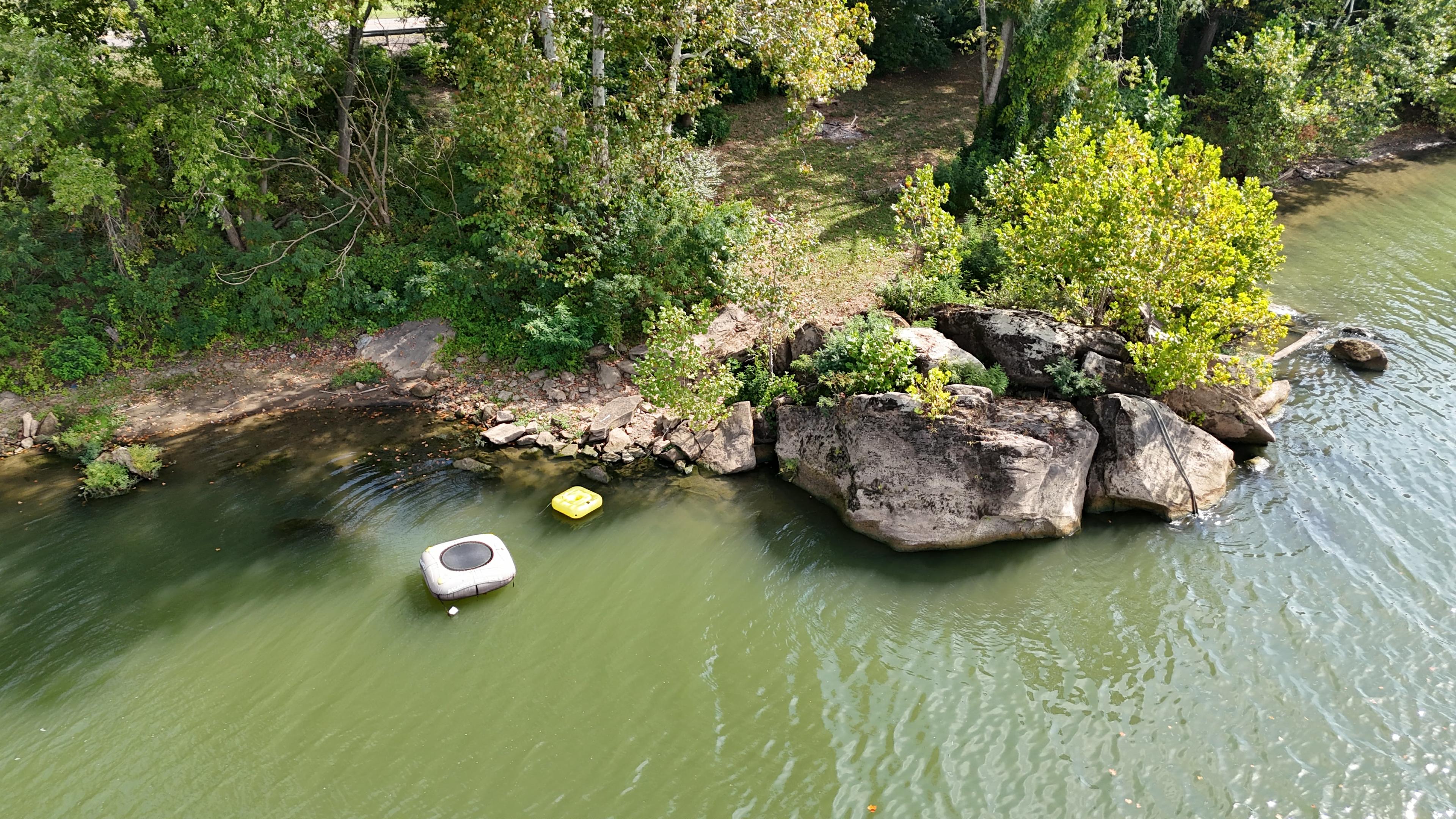 River bank camping from above with rocks for jumping and view of kayak launch site 