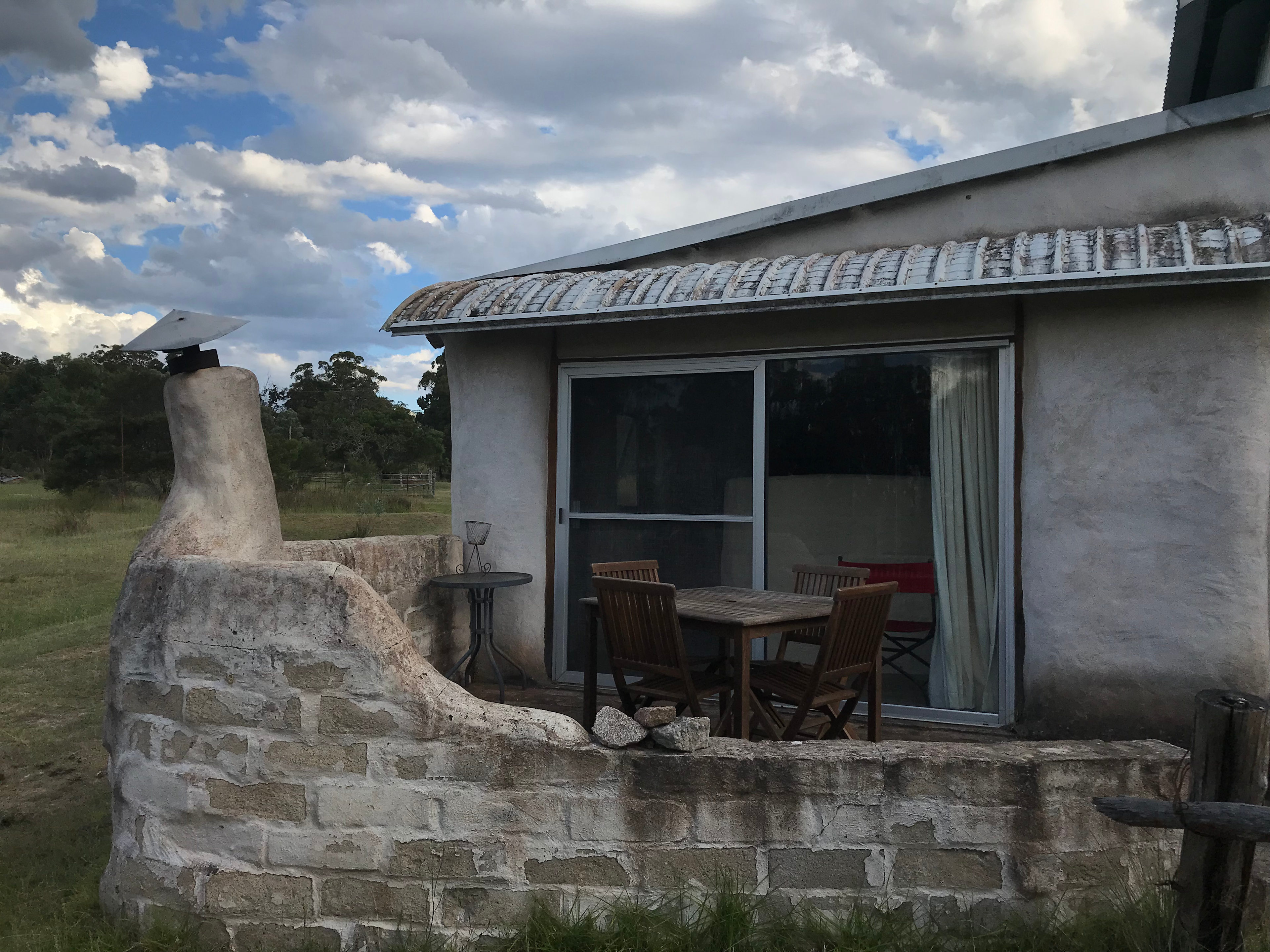 Site 2: Front of the straw bale bedroom cabin, built into our barn.  The sliding doors open onto a patio with fireplace and outdoor table and chairs. 