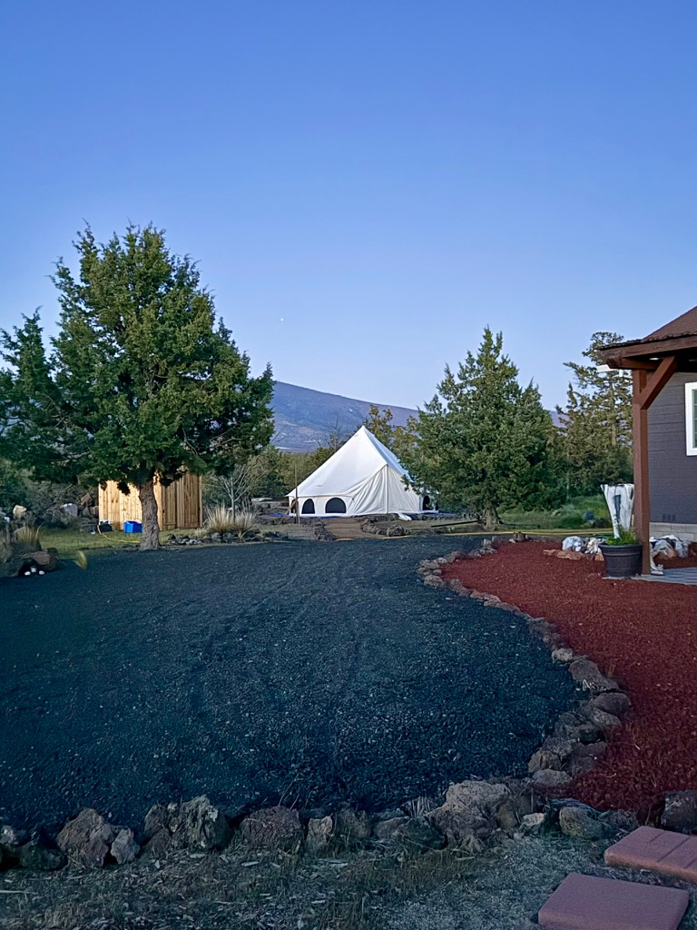 bell tent, bath house on the left, communal dining patio on the right.