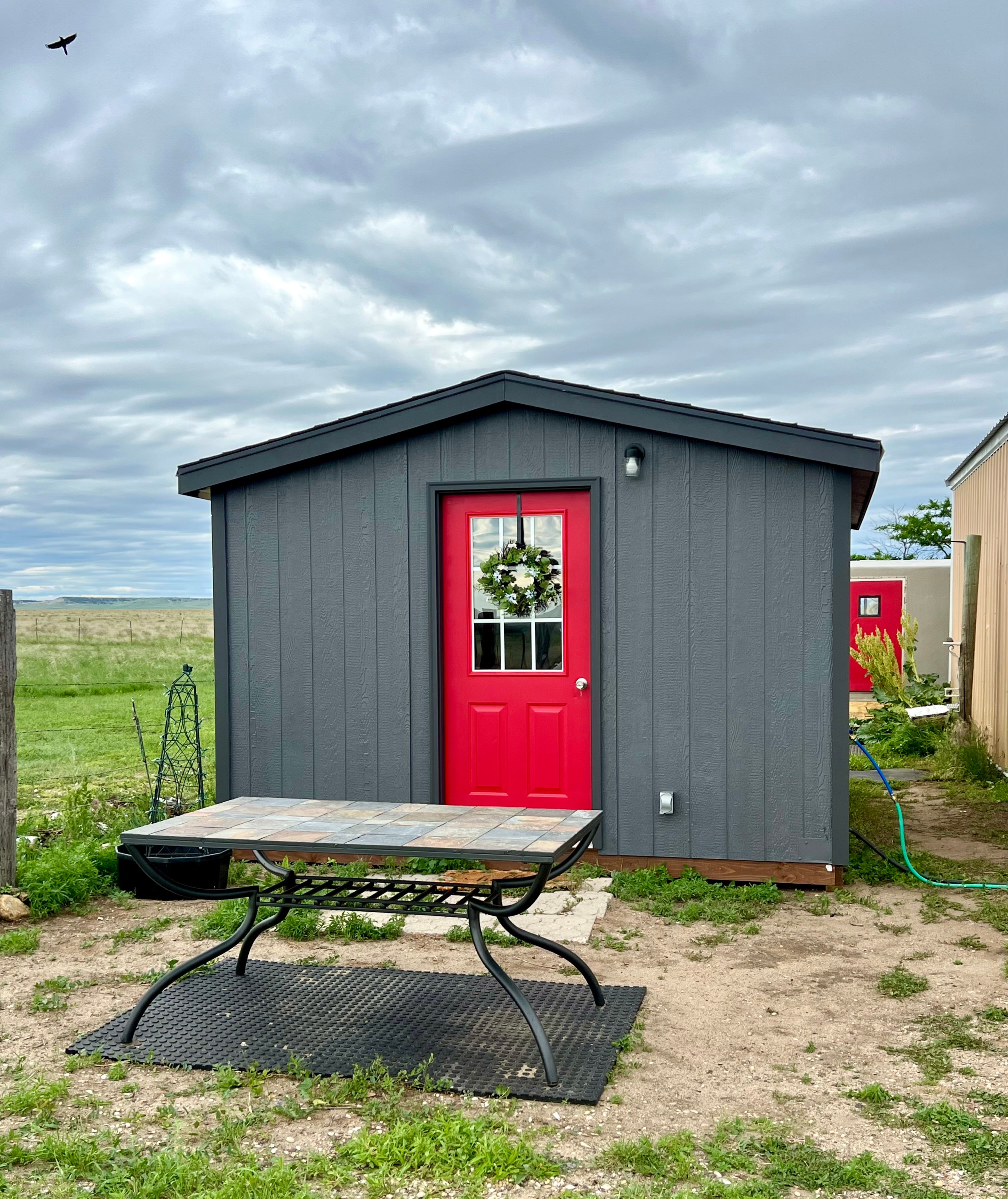 BADLANDS BUNKHOUSE, a cozy 12’ x 14’ insulated cabin with a basic tiny kitchen, stovetop and sink.