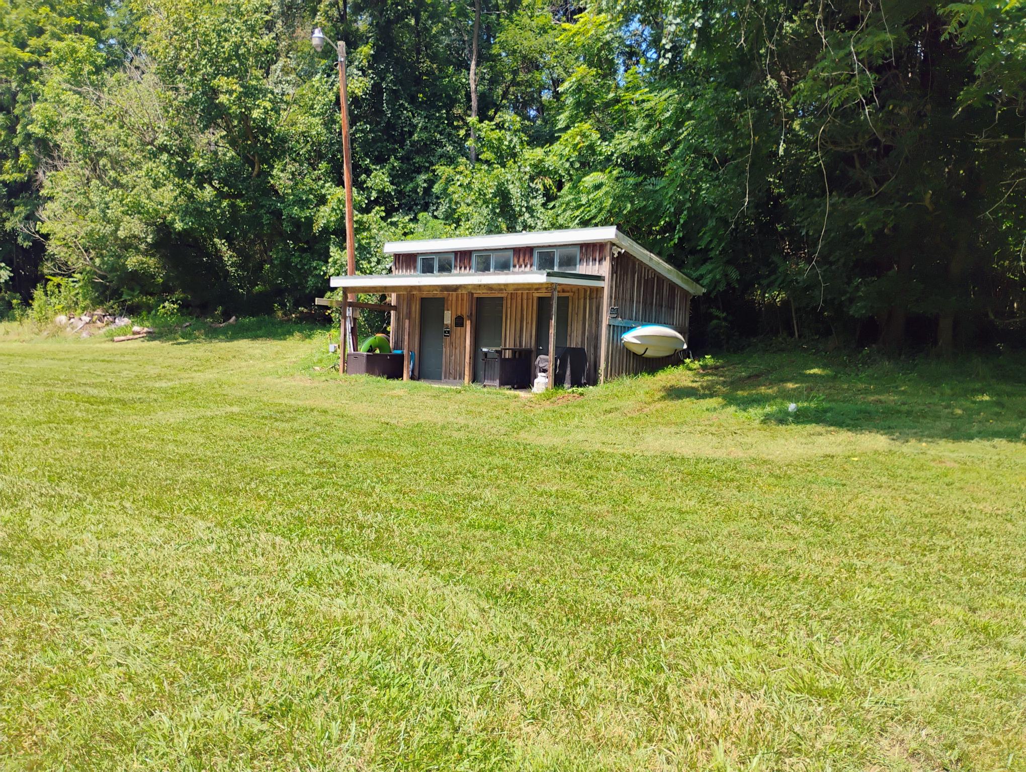 Photo of RV site and private bathhouse. RV hookups located at power pole to left of bathhouse.