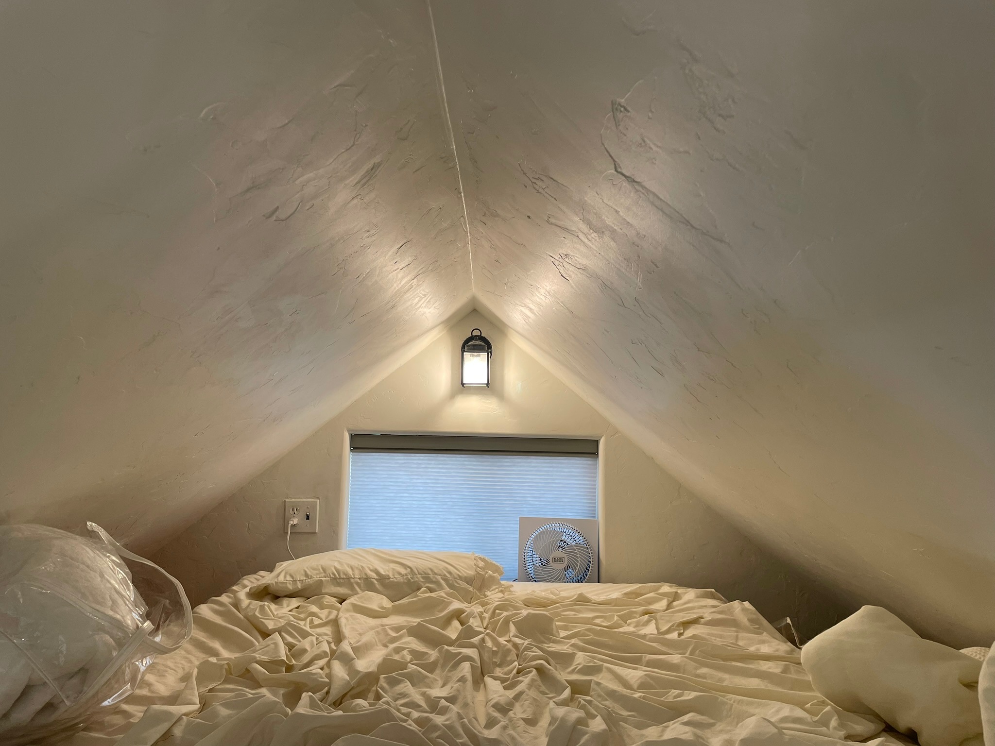 Full size bed in loft with light, outlet, window, and fan
