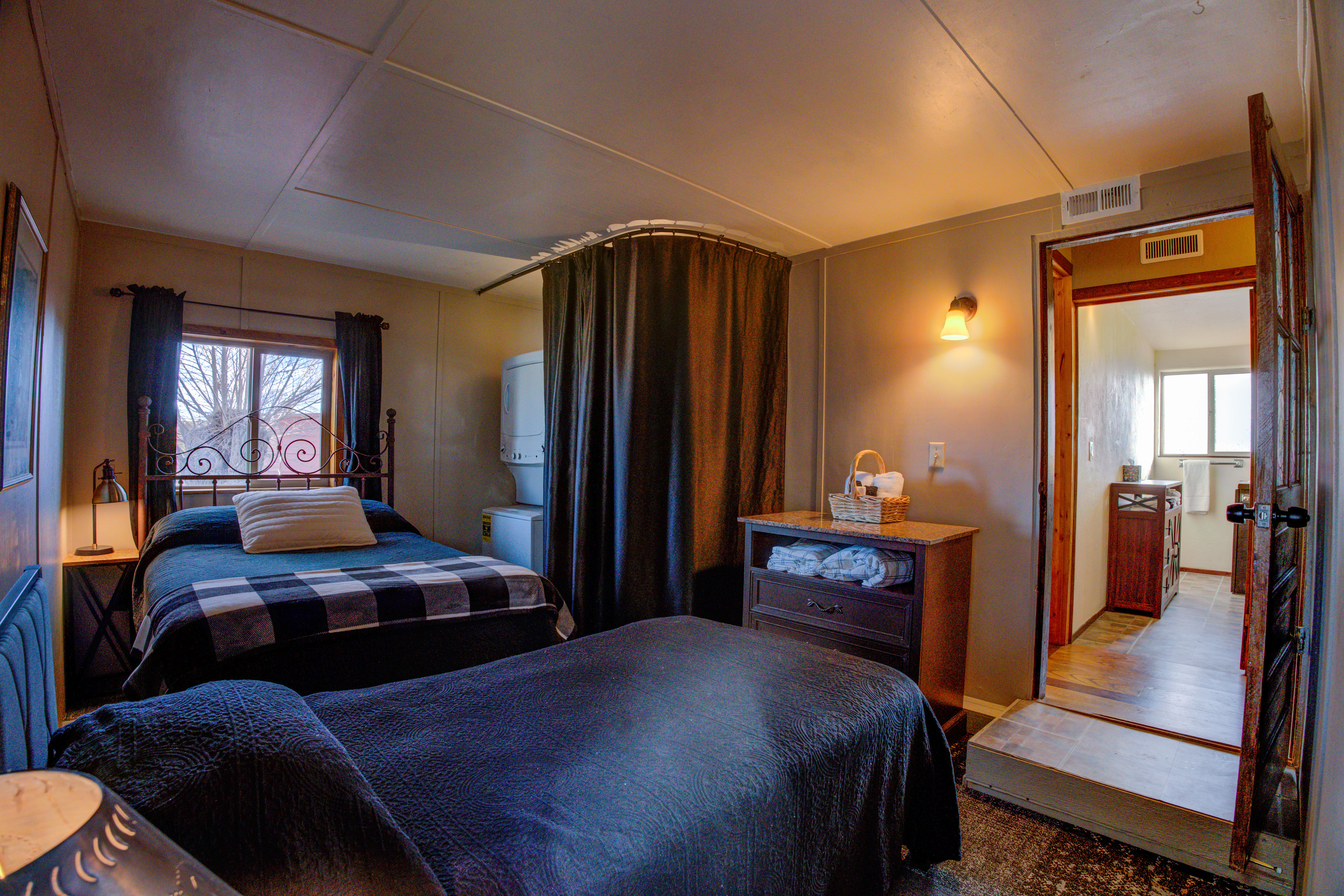 Bedroom 1 has a double bed and a single bed, dresser, closet, and a washer/dryer peeking out from the curtain.