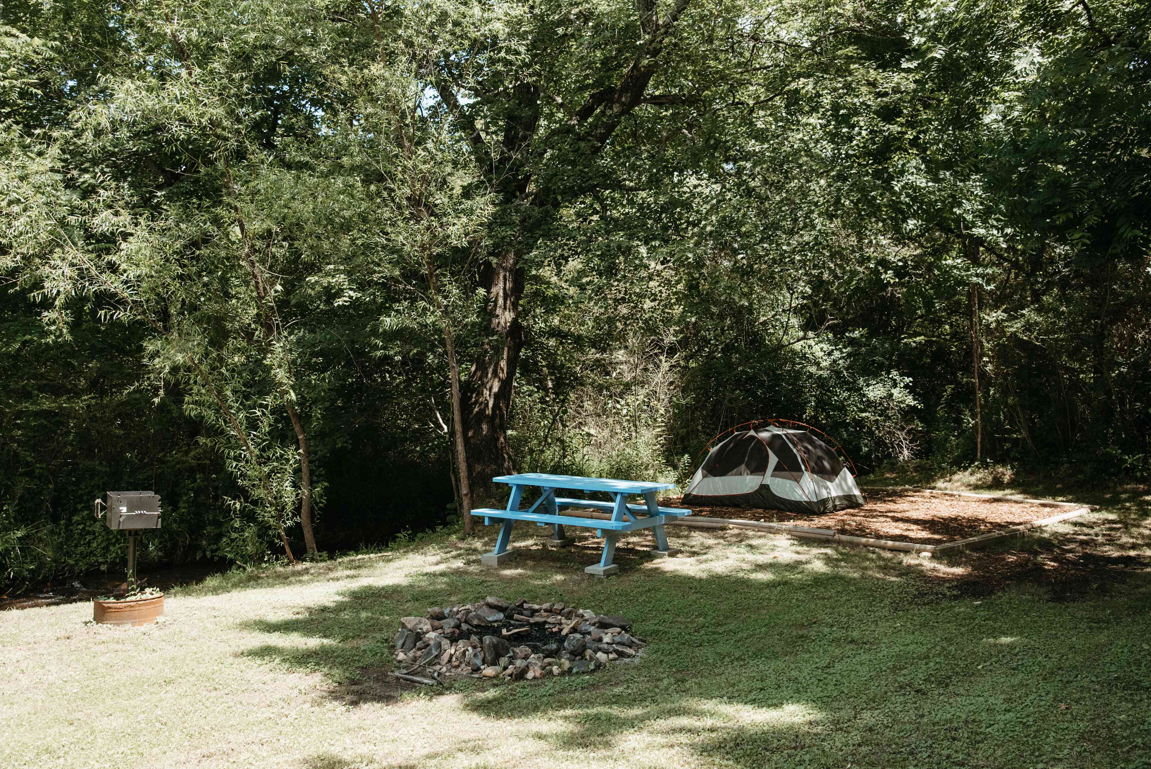 Campsite has a nice picnic table, fire pit, tent platform, and a grill.