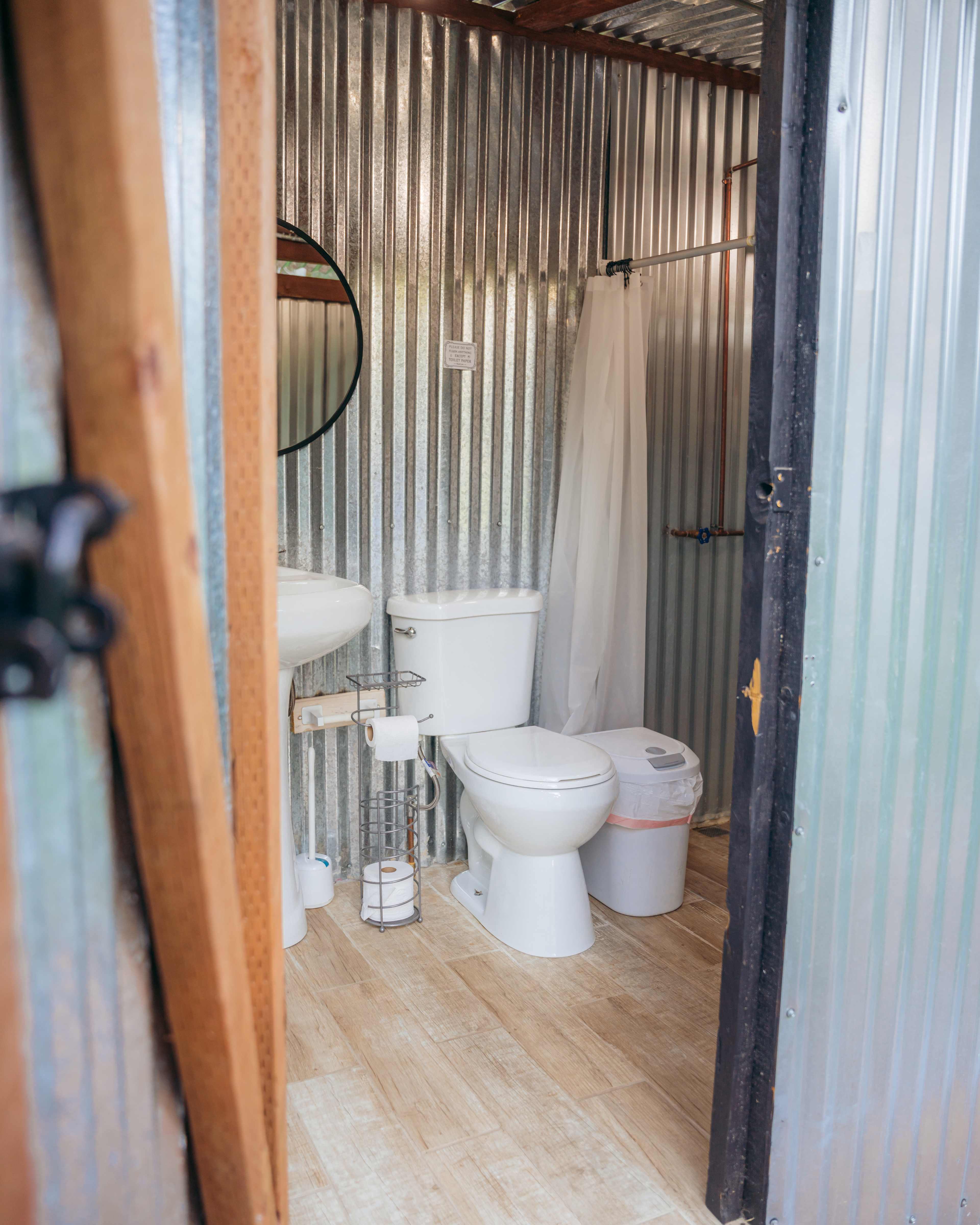 Restroom with full flush toilet, sink, shower with shampoo/conditioner/soap