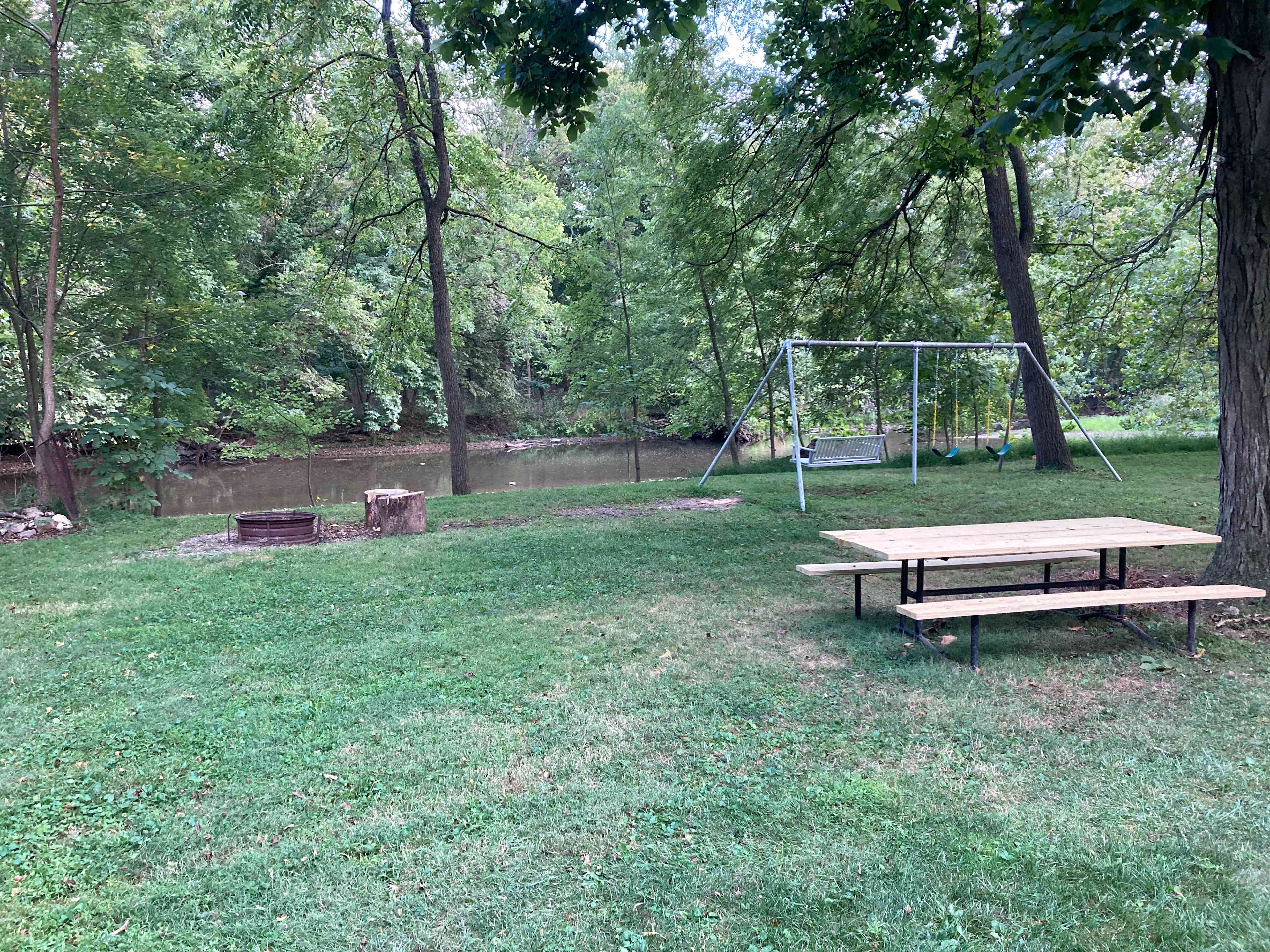 Swingset, porch swing, fire pit and picnic table overlooking the Creek